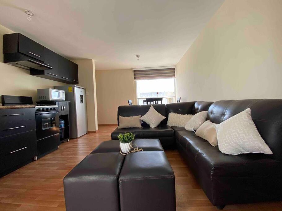 sala de estar con sofá de cuero negro y mesa en Hermoso departamento en Cuautlancingo, en Santa María Coronanco