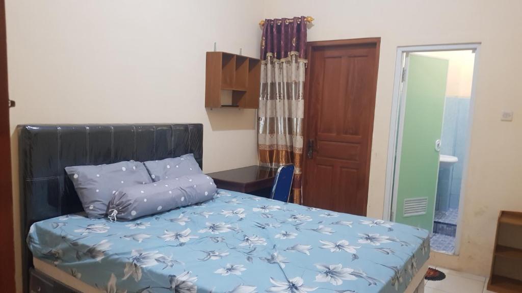 Schlafzimmer mit einem Bett mit blauer Decke in der Unterkunft Guest House GRIYA THAMRIN SYARIAH in Bonorejo