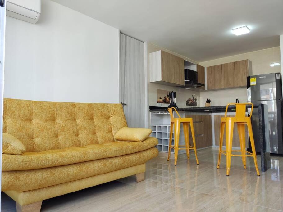 sala de estar con sofá y 2 taburetes amarillos en Apartamento en Hacienda Peñalisa Ceiba, Sol, Piscina y descanso, en Girardot