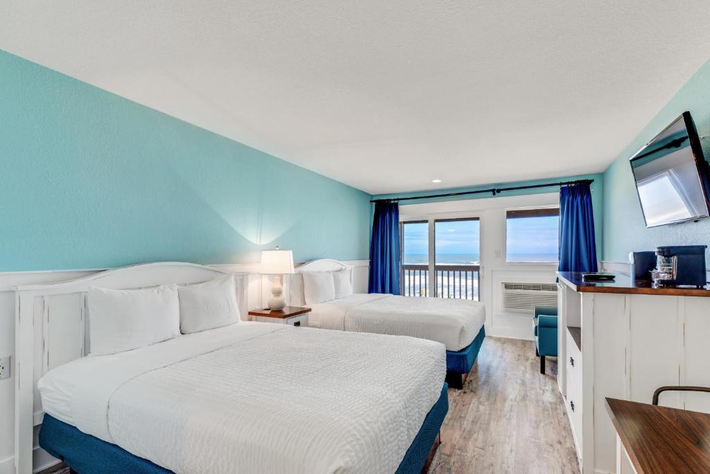 Una habitación de hotel con dos camas y balcón. en John Yancey Oceanfront Inn, en Kill Devil Hills