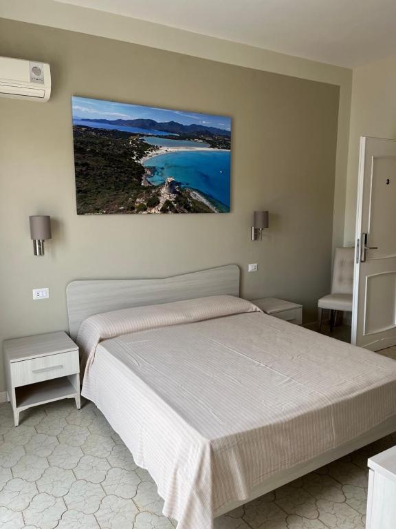 1 dormitorio con 1 cama y una pintura en la pared en Casa Tacconi, en Villasimius