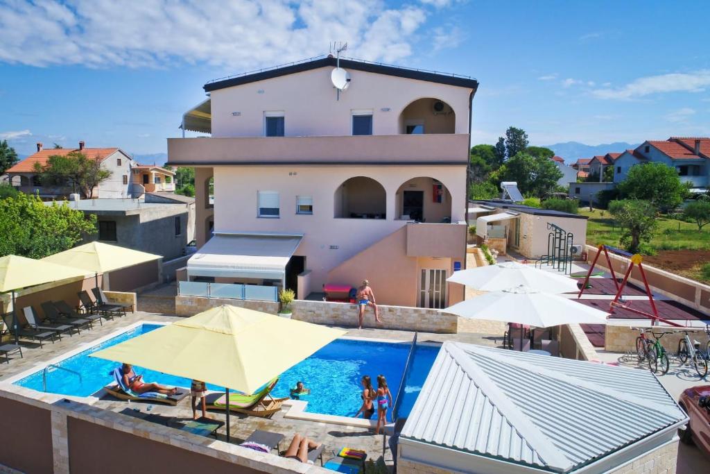 a swimming pool with yellow umbrellas and a building at Apartments Julijana 2 in Privlaka