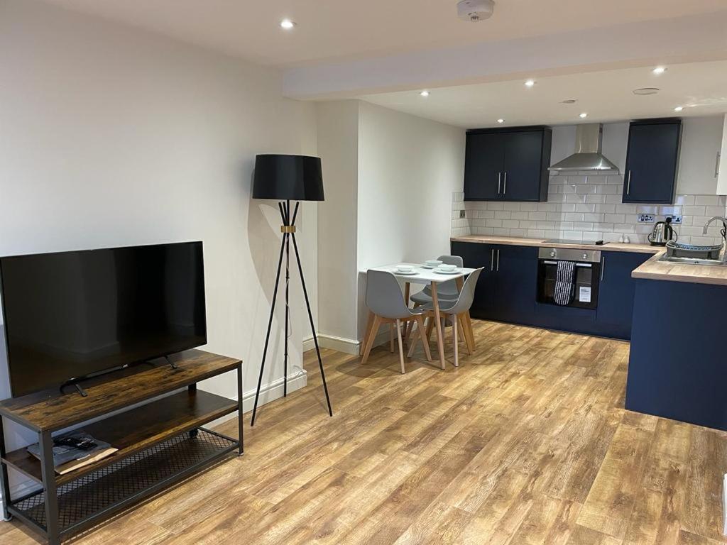 a living room with a flat screen tv and a kitchen at Newly rennovated 1-bedroom serviced apartment, walking distance to Hospital or Train Station in Newport