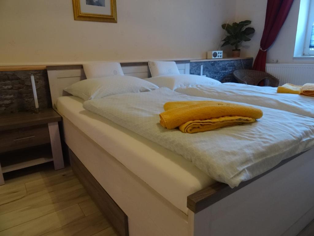 ein Bett mit einer gelben Decke darüber in der Unterkunft Pension & Gästehaus Paffrath in Großbrembach