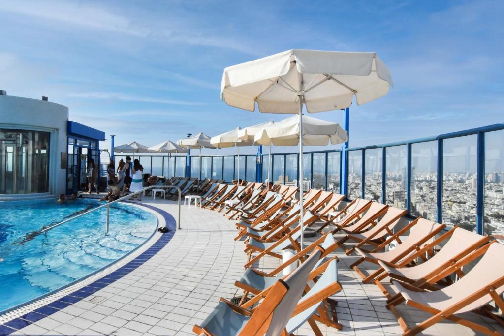 a pool with chairs and umbrellas on top of a building at Modern 2BR Condo with Sea Views at Isrotel by HolyGuest in Tel Aviv