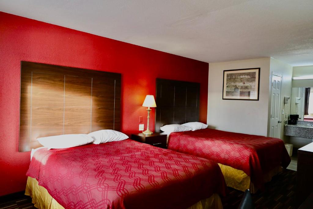 two beds in a hotel room with red walls at Rodeway Inn in Pauls Valley