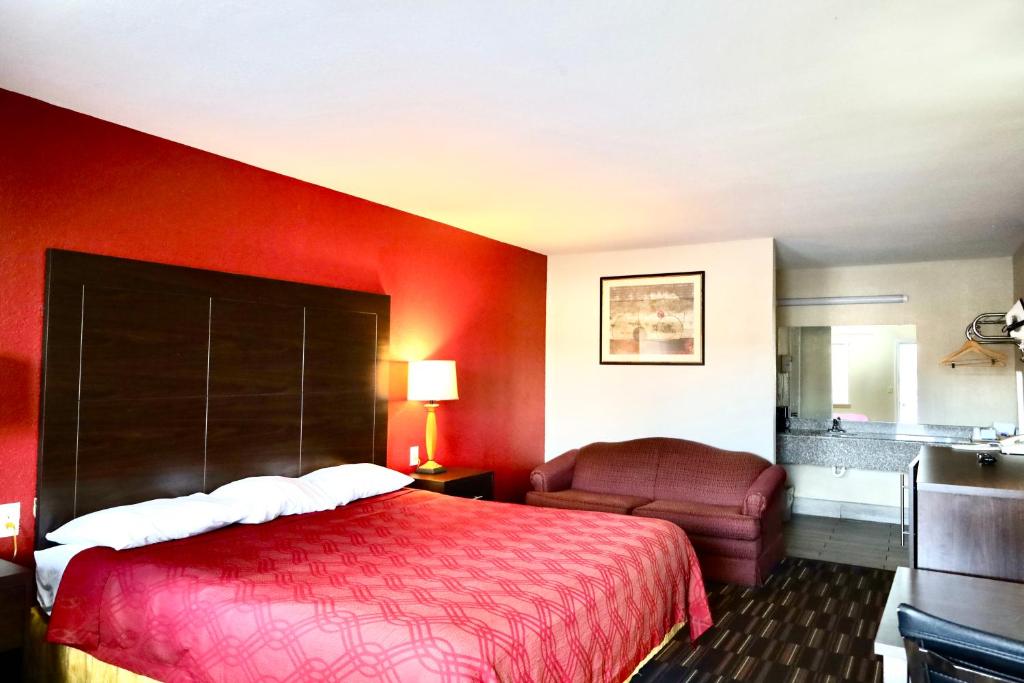 a hotel room with a red bed and a chair at Rodeway Inn in Pauls Valley