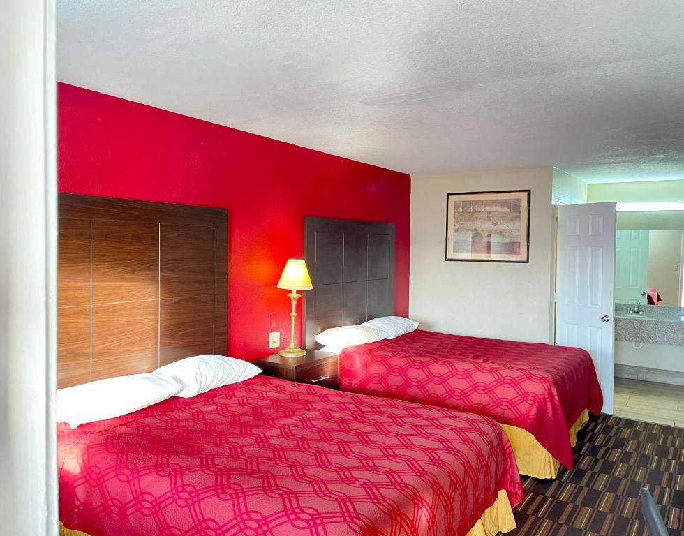two beds in a hotel room with red walls at Rodeway Inn in Pauls Valley
