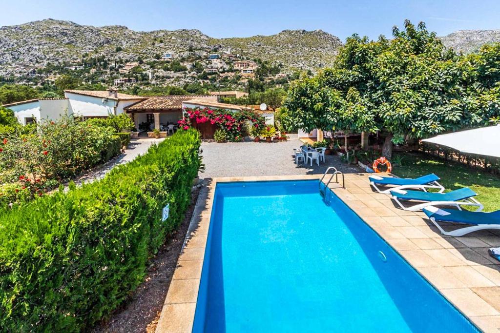 a swimming pool in a yard with chairs and a house at Villa Rosita in Pollença
