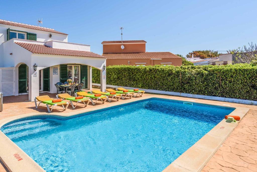 a swimming pool with chairs and a house at Villa Dion Bosch in Cala en Bosc