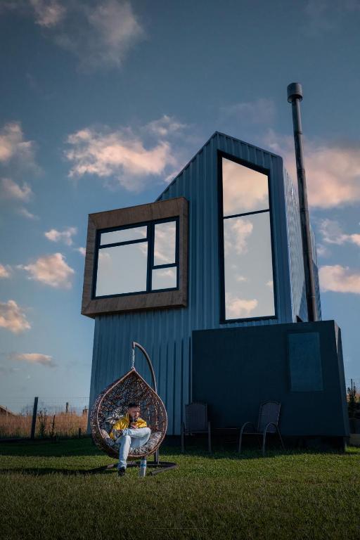 a person sitting on a swing in front of a tiny house at Tiny House Cambará in Cambará