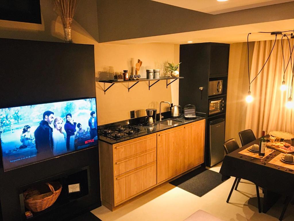 a kitchen with a flat screen tv and a kitchen with a table at Tiny House Cambará in Cambara do Sul