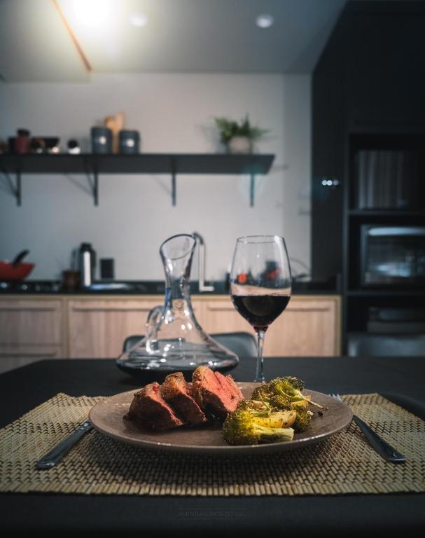 a plate of meat and a glass of wine on a table at Tiny House Cambará in Cambará