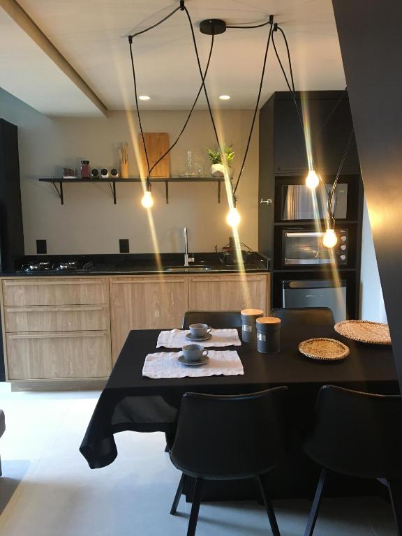 a kitchen with a black table and chairs and a kitchen with at Tiny House Cambará in Cambará