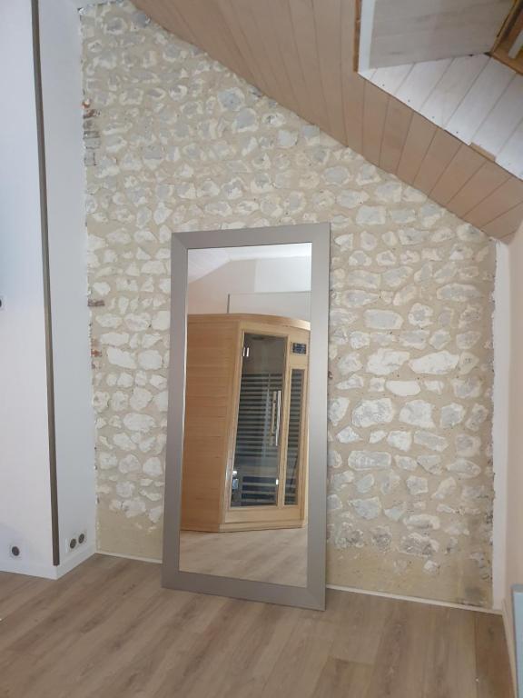 een spiegel in een kamer met een stenen muur bij La maison des galeries classé 4 étoiles in Fécamp
