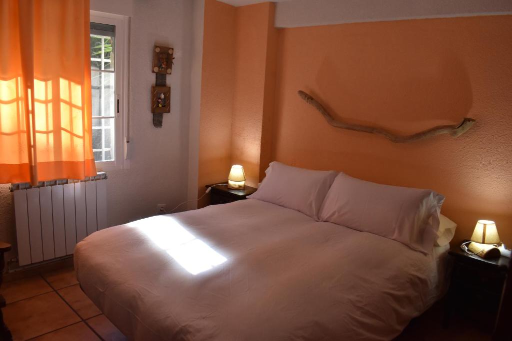 a bedroom with a large white bed with two lamps at La Rocalla del Tiétar in Sotillo de la Adrada