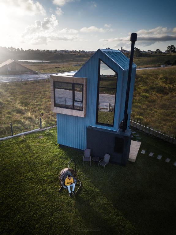 a blue tiny house with a person sitting in a swing at Tiny House Cambará in Cambará