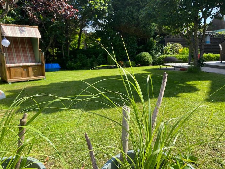 einen Garten mit einer Rasenfläche mit einer Bank in der Unterkunft Urlaubsdomizil Norden/Norddeich, mit Garten in Norden