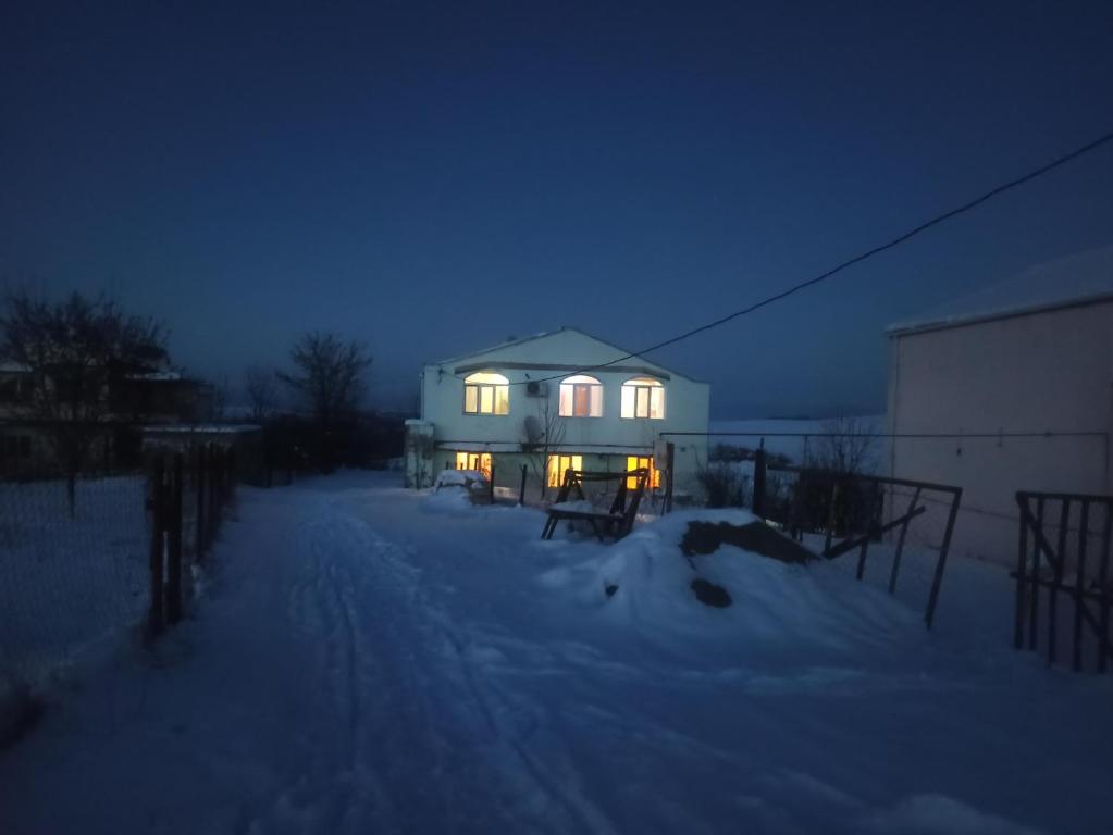 a house with lights on in the snow at night at Orchard in Quba