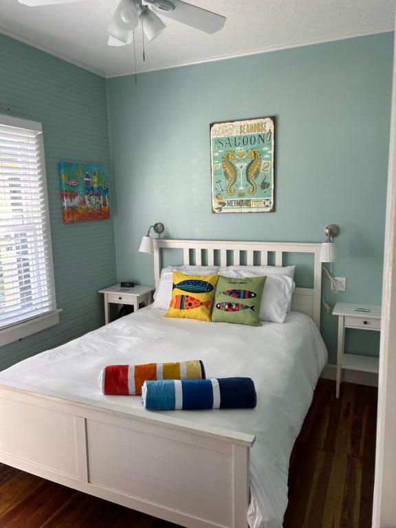 um quarto com uma cama branca e almofadas coloridas em Seahorse Bungalow em St Pete Beach