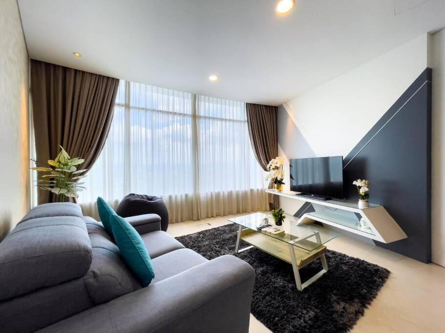 a living room with a gray couch and a television at The Luxury Penthouses Kuala Lumpur in Kuala Lumpur