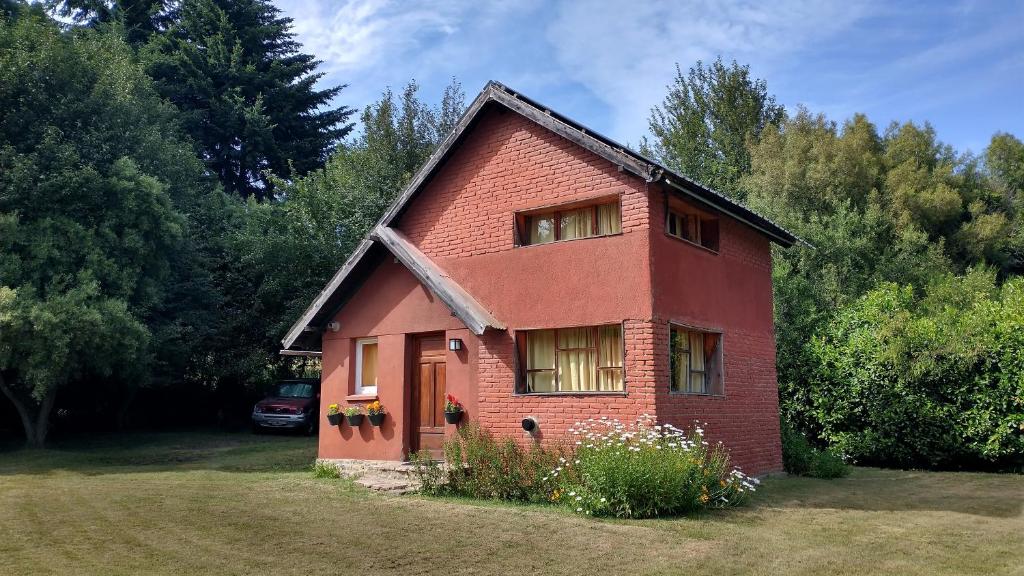 a small red brick house in a yard at La Avutarda in San Carlos de Bariloche