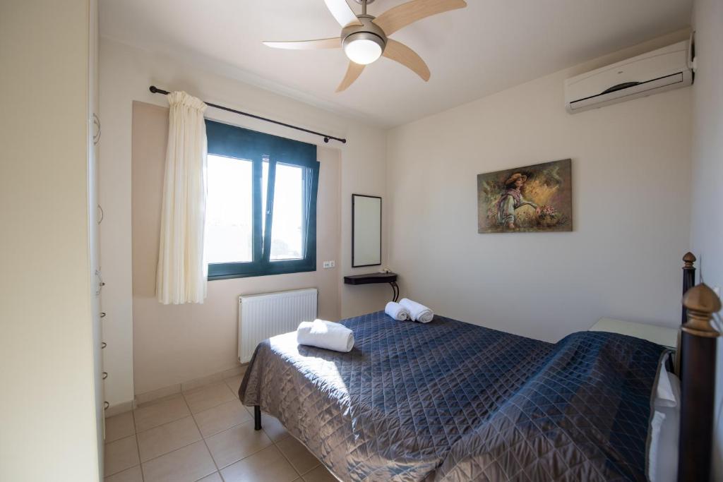 a bedroom with a bed and a ceiling fan at Portela Apartments Kampoula in Keratokampos