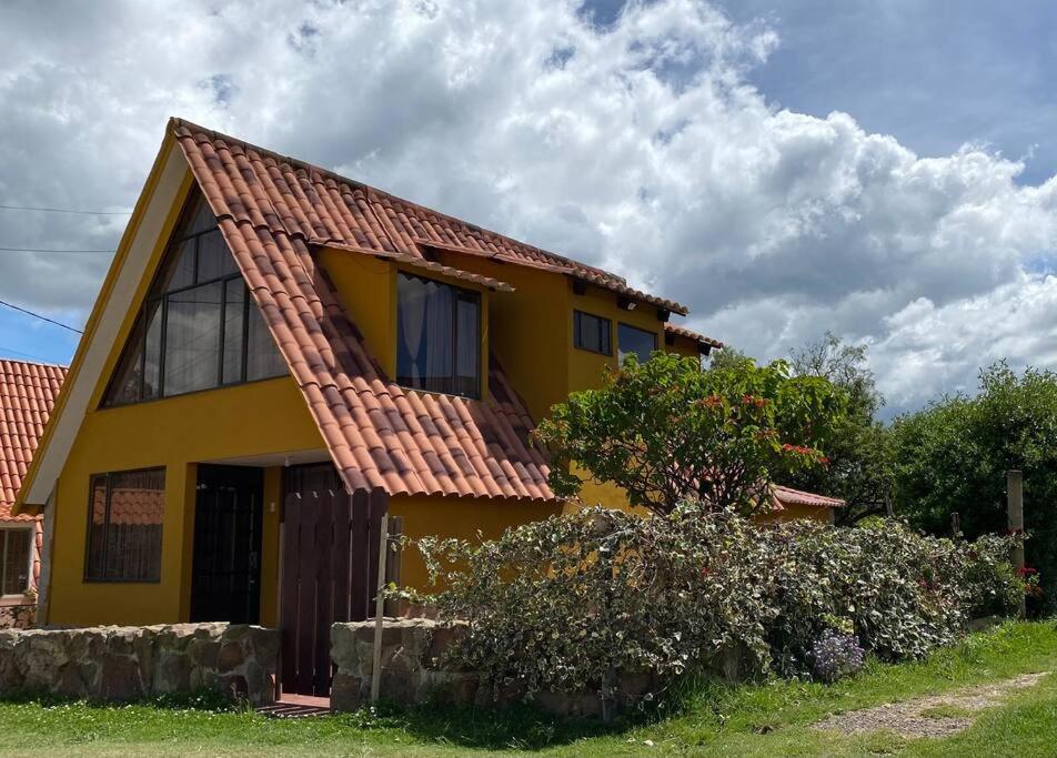 uma casa amarela com um telhado vermelho em Cabaña Villa Makus em Paipa