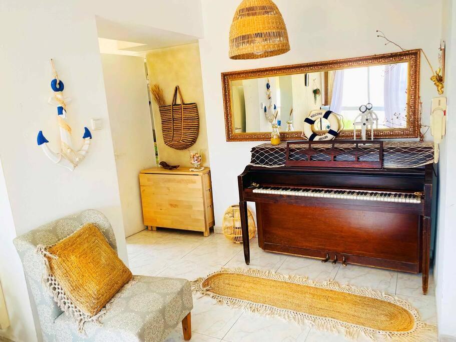 een woonkamer met een piano en een spiegel bij Piano & Sea view Golden Sea (Sunset view & beach) in Ashdod