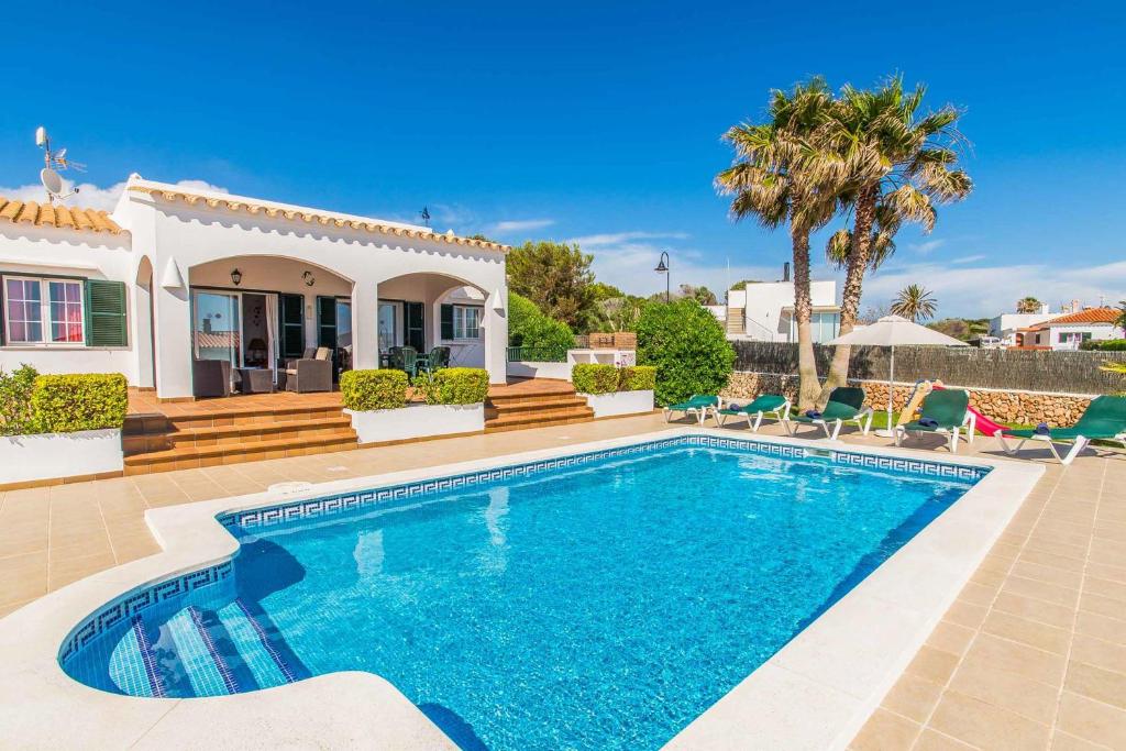 a villa with a swimming pool in front of a house at Villa Tuduri in Binibeca