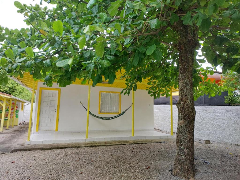 żółto-biały budynek z drzewem na pierwszym planie w obiekcie Casa Praia em Ingleses- Florianópolis w mieście Florianópolis