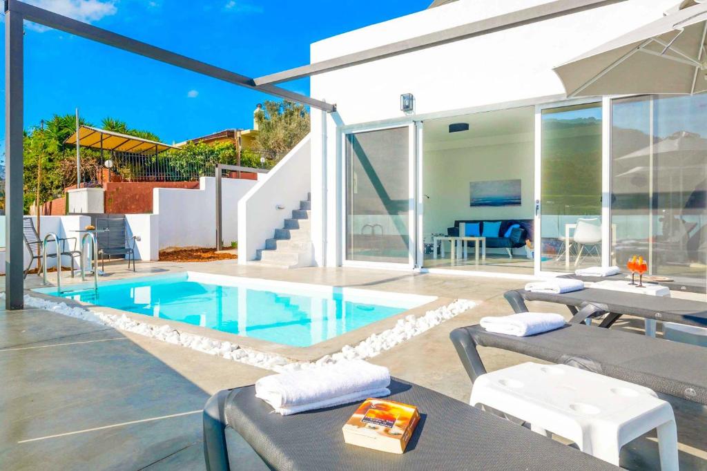 - une piscine avec des tables et des chaises à côté d'une maison dans l'établissement Villa Paradiso Ena, à Agia Pelagia