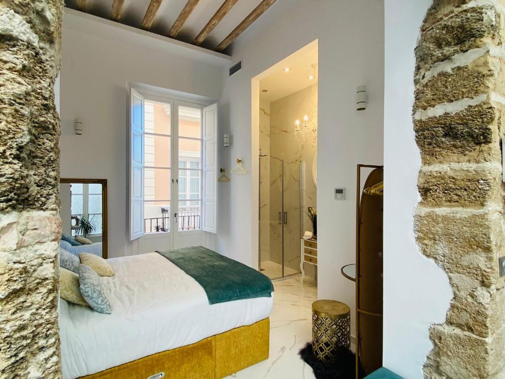 1 dormitorio con 1 cama extragrande y pared de piedra en inncadizcasa Señorial de Rivadavia en Cádiz