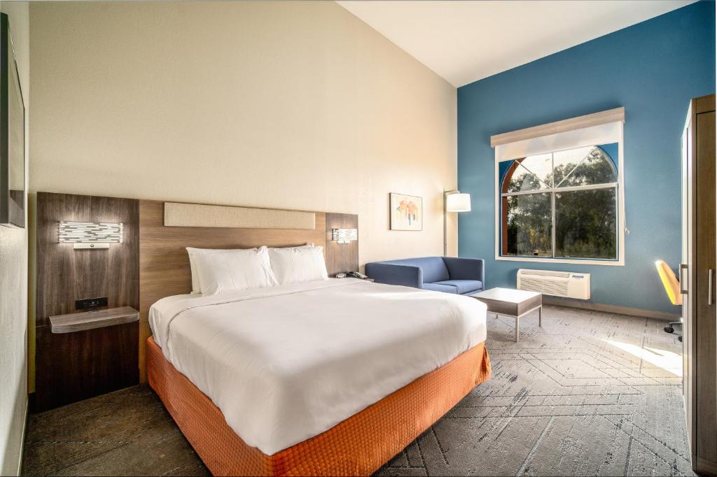 Holiday Inn Express & Suites Phoenix - Mesa West, an IHG Hotel في ميسا: غرفة نوم بسرير كبير وجدار ازرق