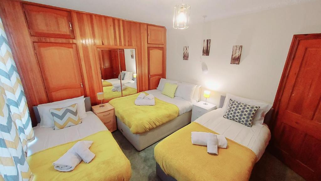 um quarto com três camas com lençóis amarelos em Rose Villa- Great For Long & Short Stays!!! em Gillingham