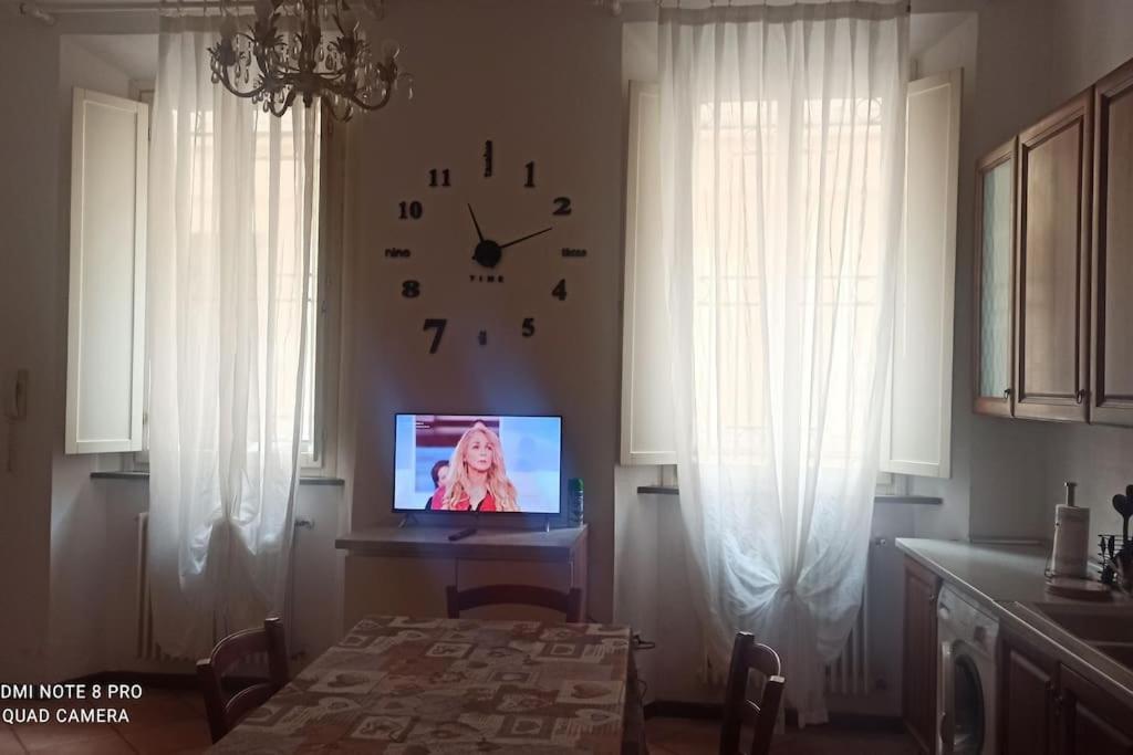 een eetkamer met een klok aan de muur en een tv bij porta merlonia house trilocale in Forlì
