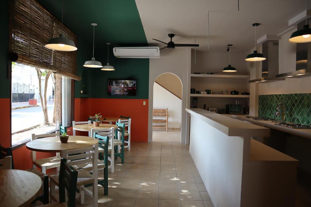 un restaurante con mesas, sillas y paredes verdes en 3B Wellness Hostel, en Playa del Carmen