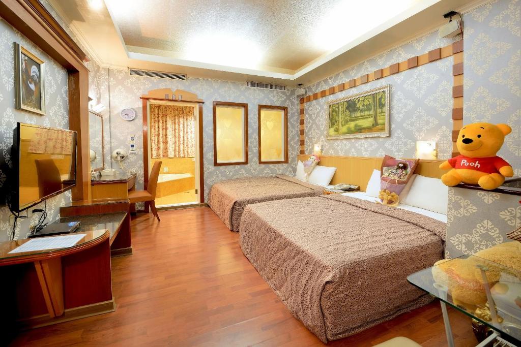 Cette chambre d'hôtel comprend deux lits et un ours en peluche. dans l'établissement Holland Village Motel, à Anping