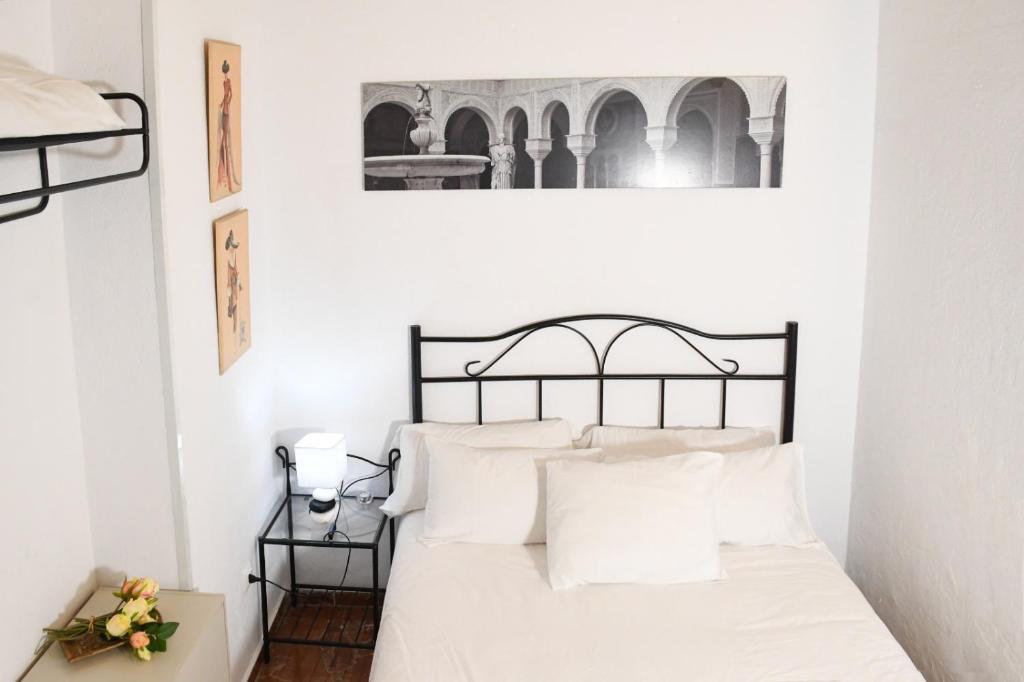 1 dormitorio con cama blanca y negra con almohadas blancas en Apartamento Descalzos, en Sevilla
