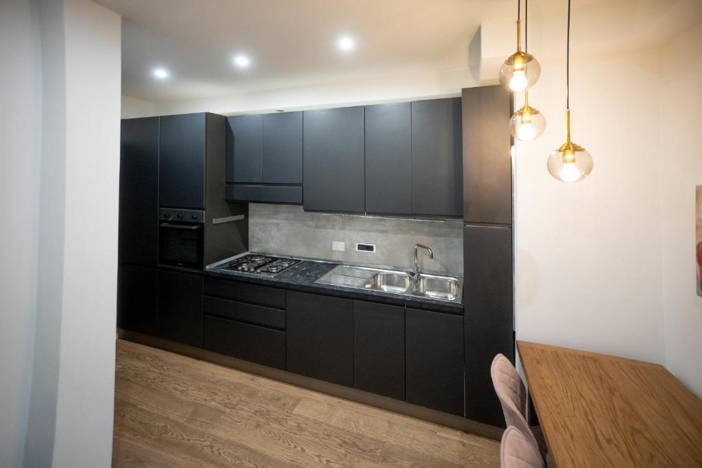 a kitchen with black cabinets and a wooden table at Angelico Luxury House in Rome