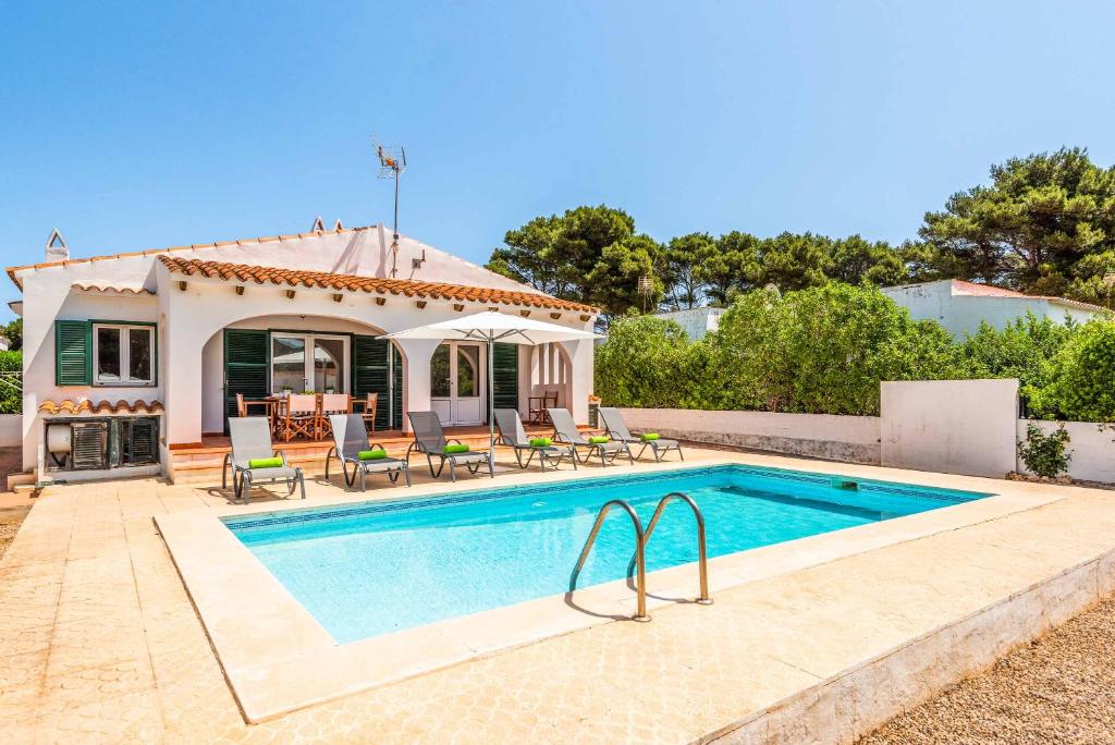 a villa with a swimming pool in front of a house at Villa Xaloc in Port d'Addaia