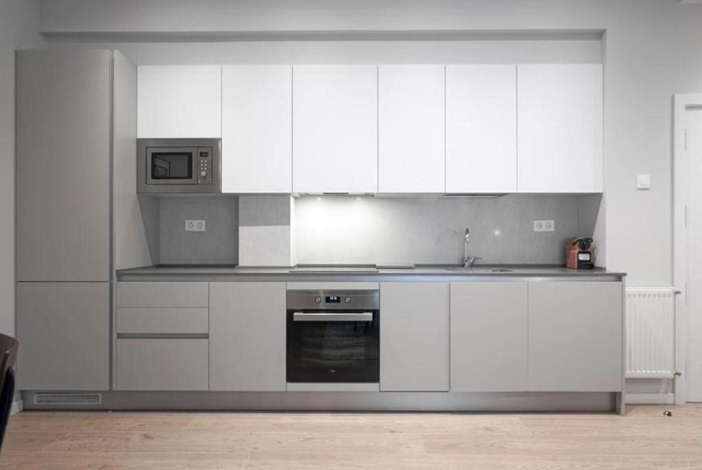 a kitchen with white cabinets and a sink and a microwave at Apartamento Urumea by SanSe Holidays in San Sebastián