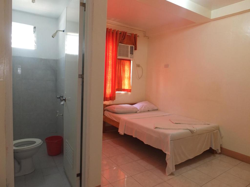 a room with two beds and a bathroom with a toilet at Constrell Pension House in Tagbilaran City