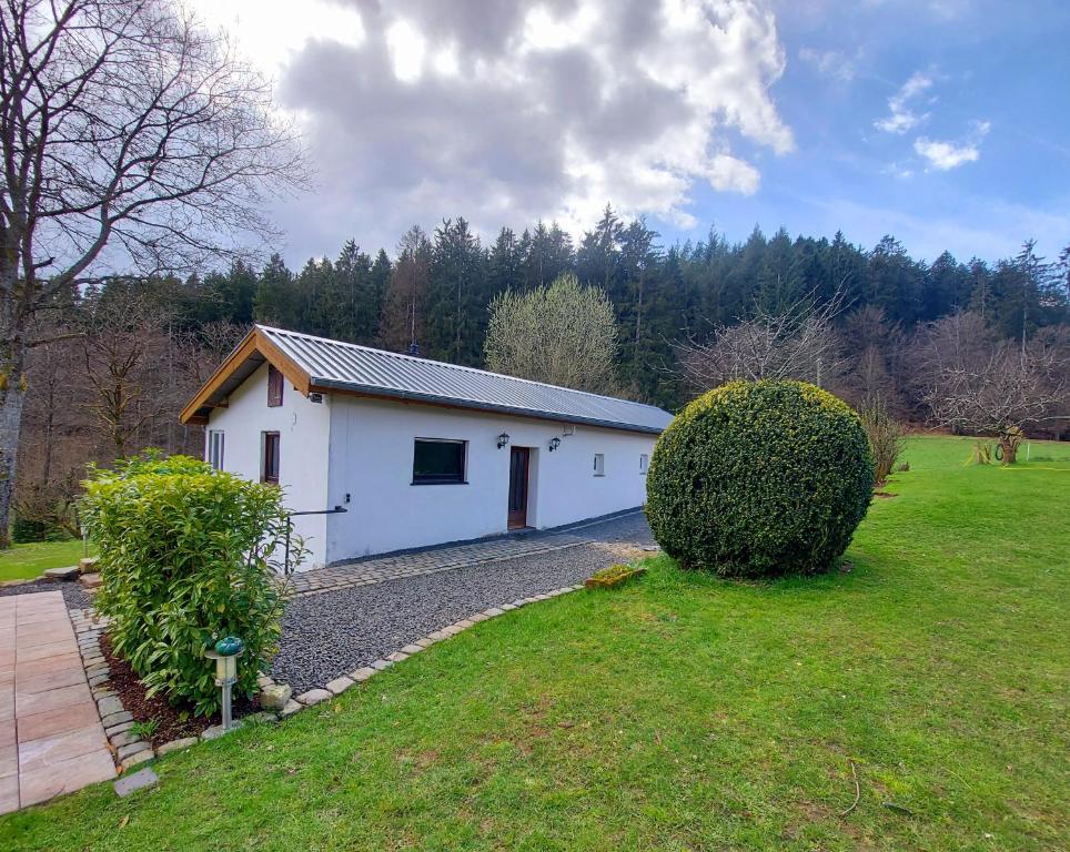 a white building in a yard with a bush at Ferienhaus Berghof Usch 