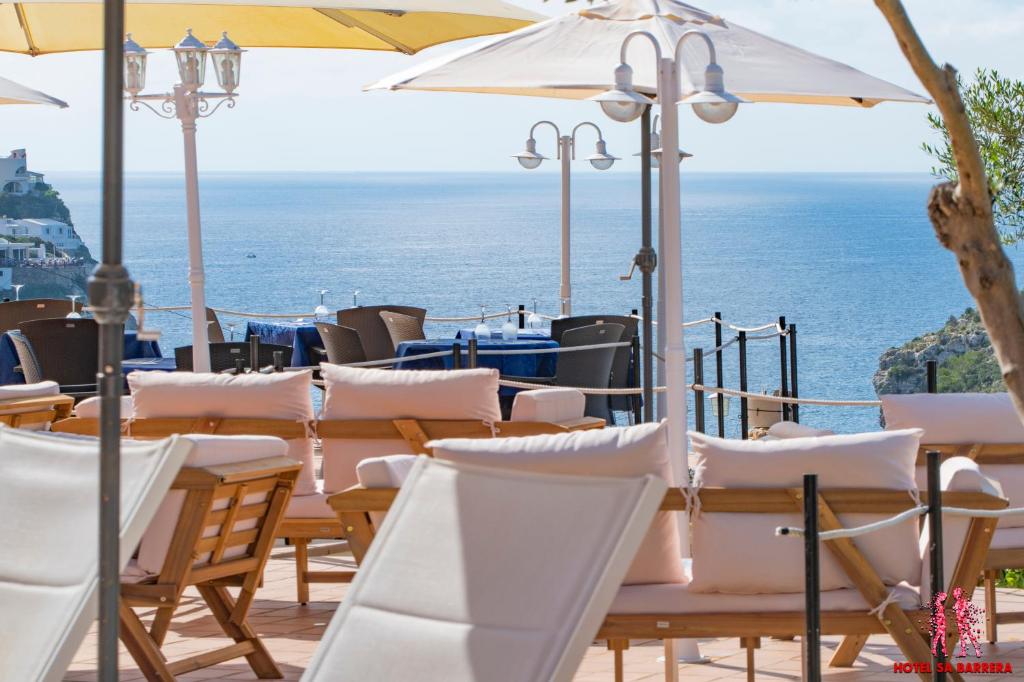 une rangée de tables et de chaises avec l'océan en arrière-plan dans l'établissement Hotel Sa Barrera - Adults Only, à Cala'n Porter