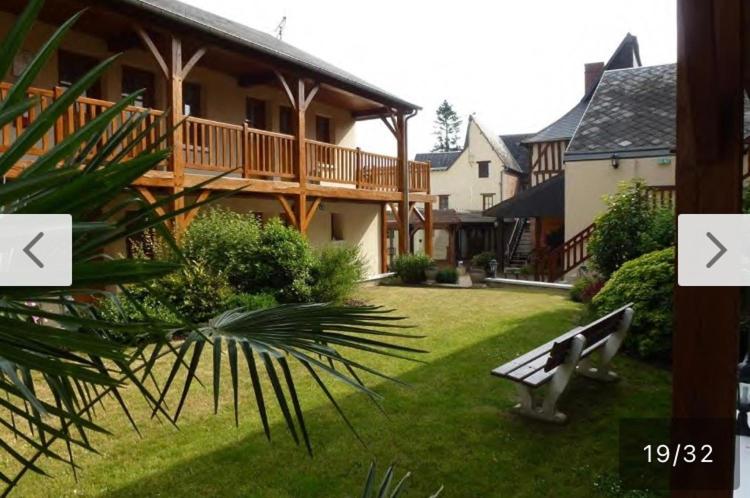 een parkbankje in de tuin van een huis bij Résidence Normandie in Conches-en-Ouche