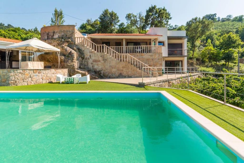 a villa with a swimming pool in front of a house at Casa da Barragem Douro in Cinfães