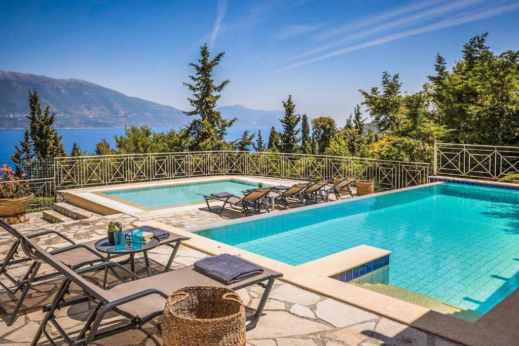 a swimming pool with chairs and a table next to it at Villa Astria in Kefallonia