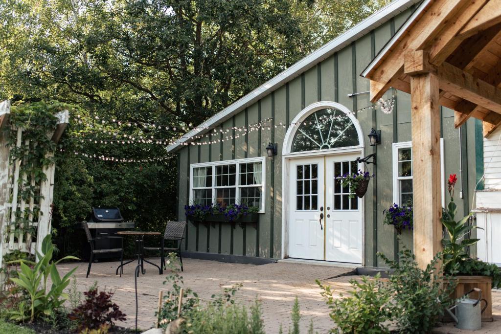 a green house with a white door and a patio at Rosedale Chapel Bed and Breakfast in Steinbach