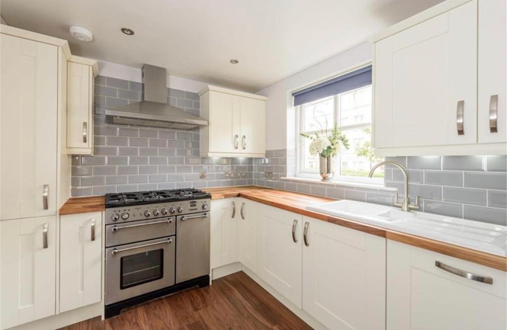 Una cocina con gabinetes blancos y un horno de estufa. en Cosy Roseburn Apartment, Edinburgh - 2 Bedrooms, FREE PARKING, en Edimburgo